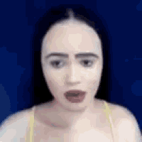a close up of a woman 's face with a blue background and a yellow top .