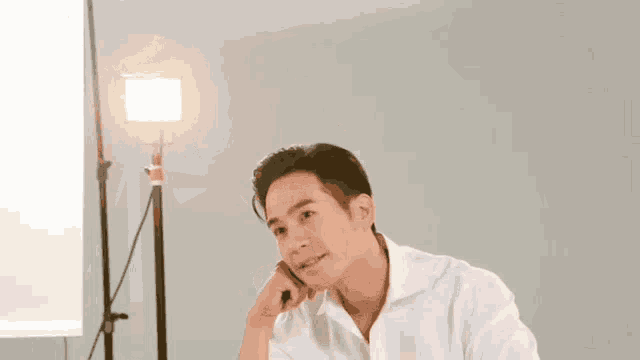 a man in a white shirt is sitting in front of a light