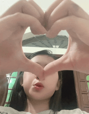a girl making a heart shape with her hands in front of her face