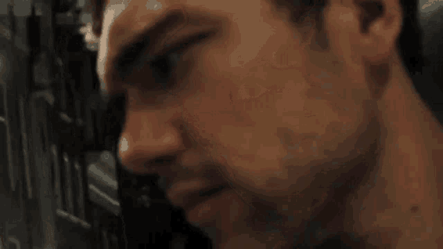 a close up of a man 's face with a beard and a serious look on his face .