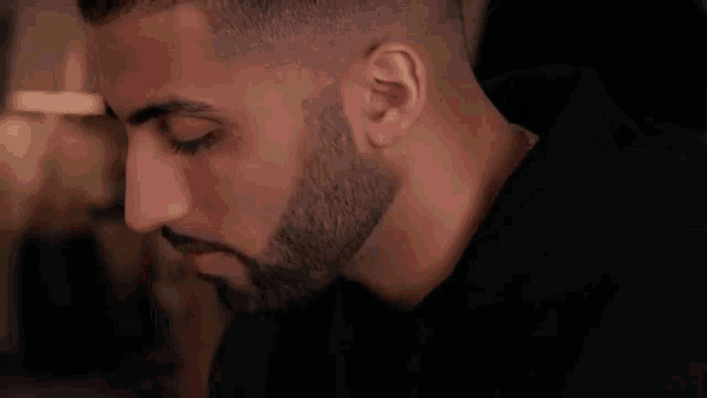a close up of a man 's face with a beard wearing a black shirt .