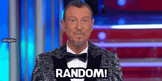 a man in a tuxedo and bow tie is standing on a stage and says random .