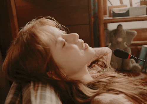 a woman laying on a bed with a microphone behind her