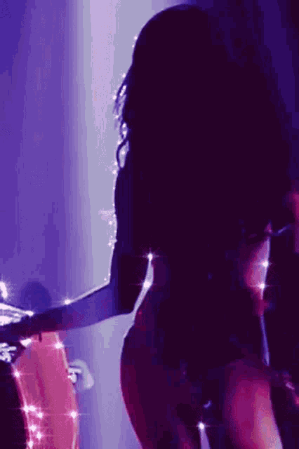 a woman is dancing in a dark room with purple lights .