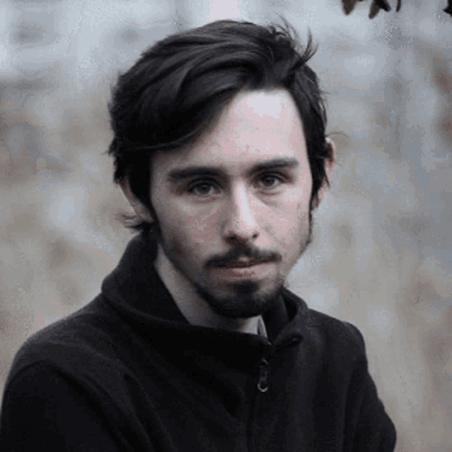 a man with a beard is wearing a black sweater