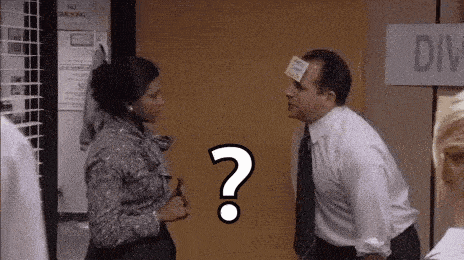 a man and a woman are standing next to each other in a room with a question mark on their foreheads .