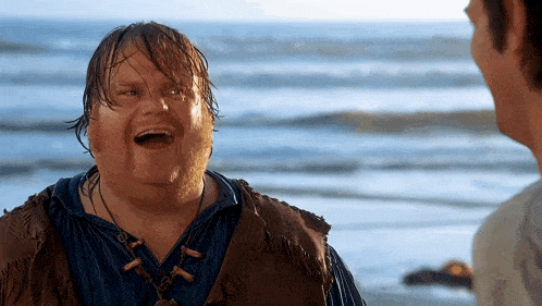 a man is laughing while standing on a beach near the ocean