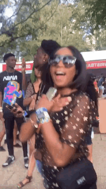 a woman wearing sunglasses is standing in front of a man wearing a shirt that says nana