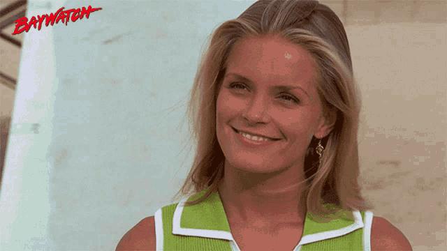 a woman is smiling in front of a sign that says baywatch on it