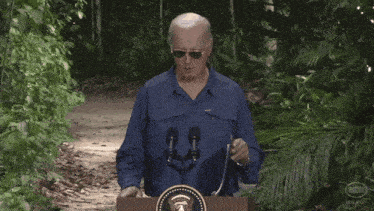 a man walking down a path with a podium that has the seal of the president on it