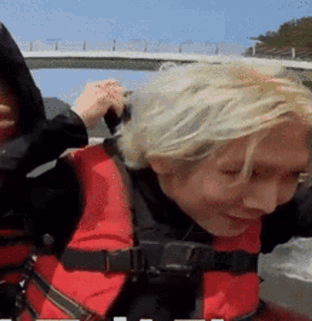 a woman wearing a life vest is being held by another woman