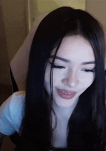 a woman with long black hair and a white shirt smiles