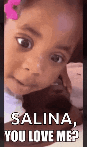 a little girl with a pink flower in her hair is making a funny face and says `` salina , you love me ? ''