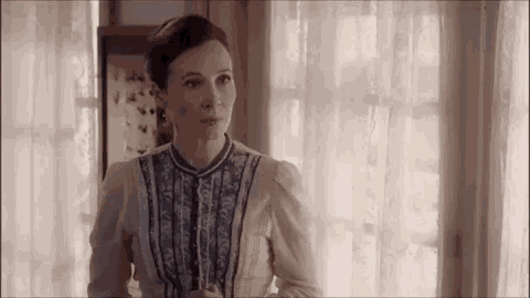 a woman is standing in front of a window in a room .
