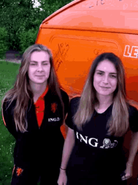 two women standing next to each other one wearing an ing shirt