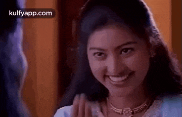 a woman is smiling and waving at a man in a movie .
