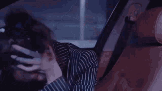 a woman is sitting in a car holding her head .