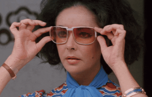 a woman wearing a blue shirt and white sunglasses