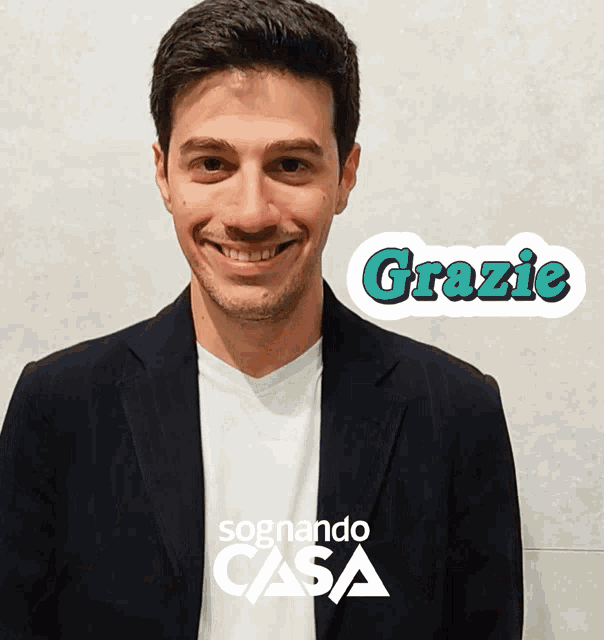 a man is smiling in front of a sign that says " grazie "