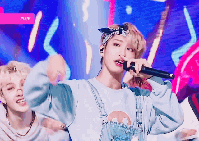 a man in overalls is singing into a microphone with the word pixie above him
