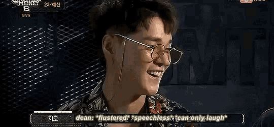 a young man wearing glasses is laughing while talking on a television show .