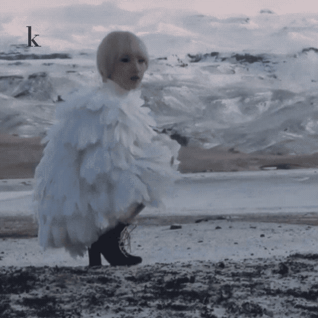 a woman in a white feathered dress is standing on a snowy hillside .