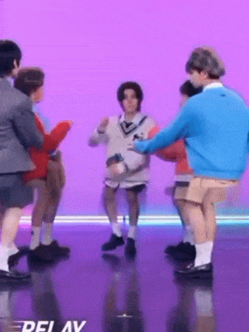 a group of people are dancing on a stage with a purple background .