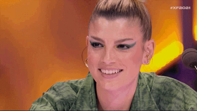 a woman in a green shirt smiles in front of a microphone with the hashtag xf2021