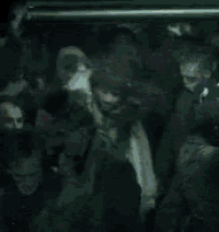a group of people are gathered in a dark room with a purple light shining on them