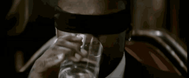 a blindfolded man drinking from a glass