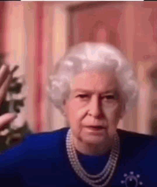 queen elizabeth ii is wearing a blue dress and a pearl necklace while talking on a video call .
