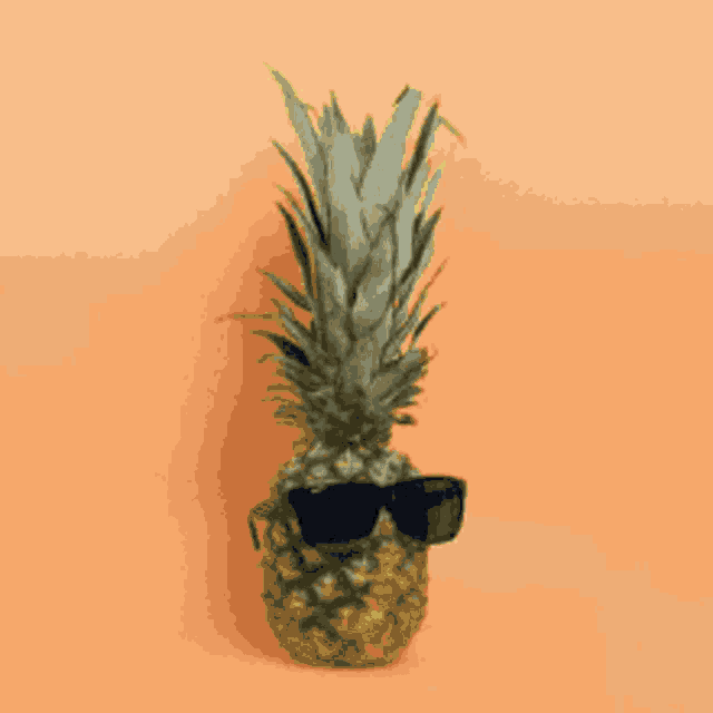 a pineapple wearing sunglasses against a pink background