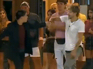 a group of people standing in a room with a man in a white shirt standing in the middle .