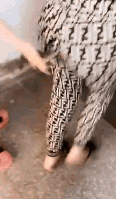 a person wearing a pair of fendi pants is standing on a tiled floor .
