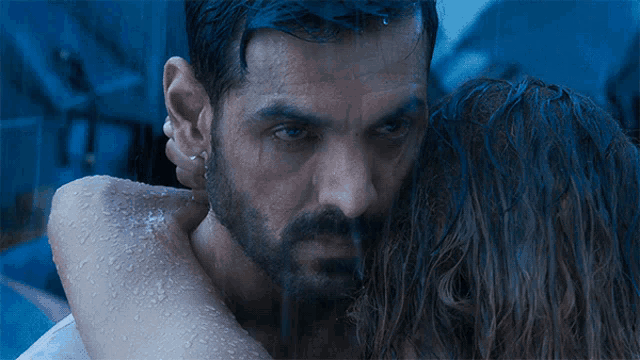 a man and woman are hugging in the rain