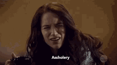 a woman is sitting on a couch holding a cup of coffee and making a funny face .