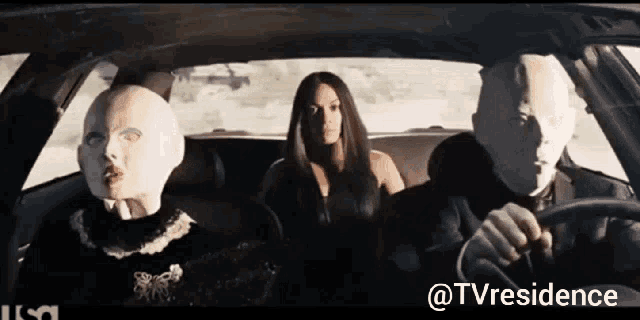 a man is driving a car with two masked people in the back seat ..