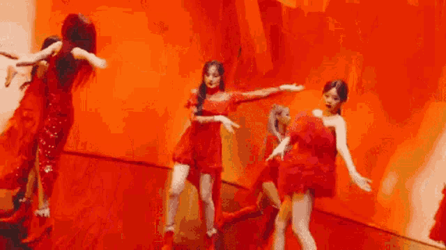 a group of women are dancing on a stage in front of a red wall .