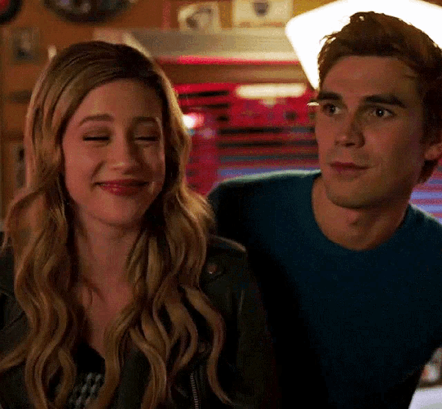 a man and a woman are sitting next to each other in a room and smiling .