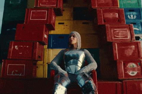 a woman in a knight 's outfit sits in front of a stack of red crates