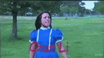 a girl in a blue dress is standing in a field