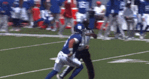 a new york giants football player is being tackled by a referee on the field
