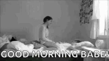 a woman is sitting on top of a man on a bed and says `` good morning babe '' .