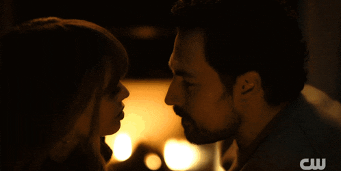 a close up of a man and woman kissing with a cw logo in the background