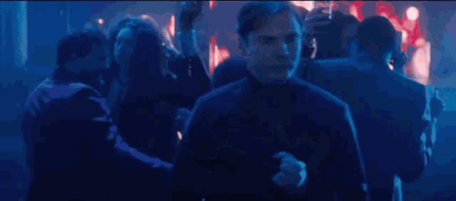 a man is dancing in a crowd of people at a party in a dark room .