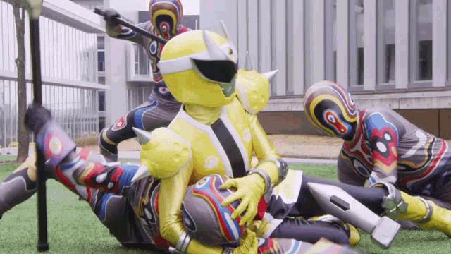a group of superheros are laying on the grass and one of them is wearing a yellow helmet