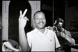 a man giving a peace sign in front of a shark mask