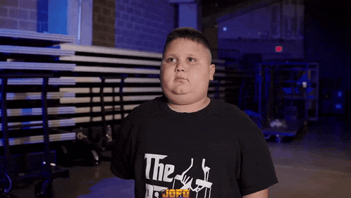 a boy wearing a black t-shirt that says " the godfather "