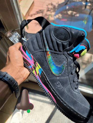 a person is holding a pair of nike air force 1 sneakers