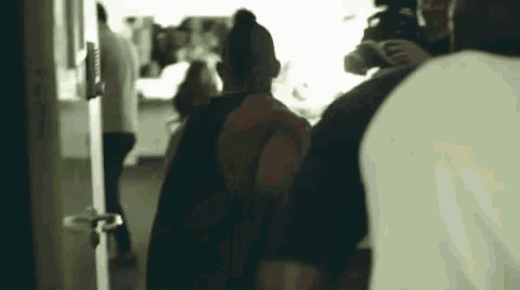 a group of people are walking down a hallway and talking to each other .